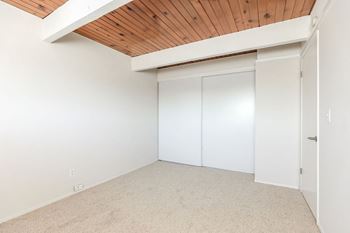 A bedroom with white walls and a wood ceiling